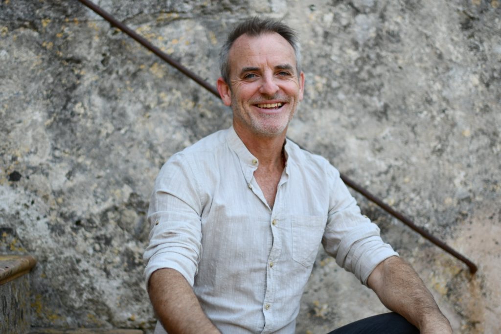 Photo portrait of Breath work Faciliter Sean Kranti Herron in white shirt sitting at Dima Mallorca